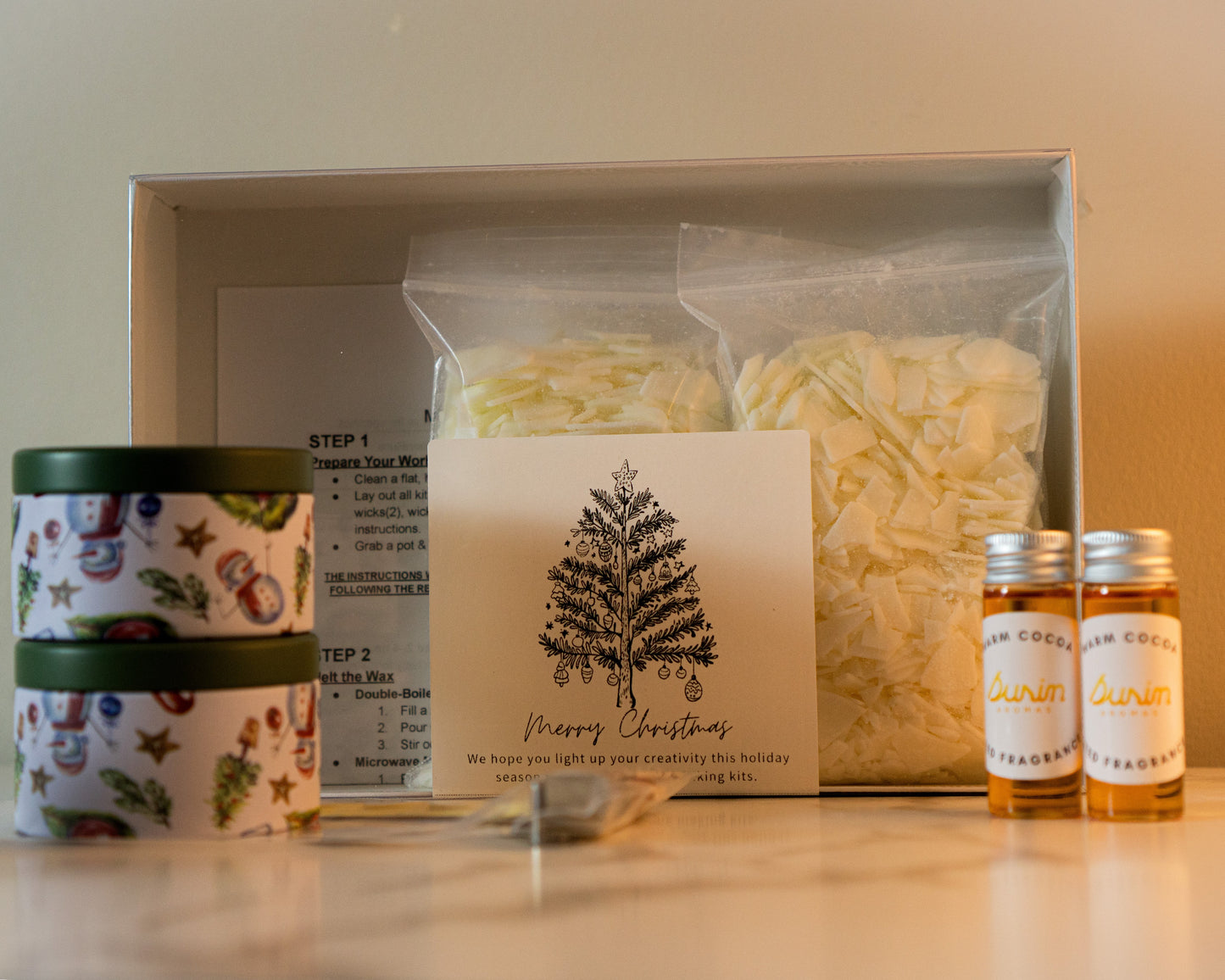 Gift set with candles, a card, and bottles on a white surface.