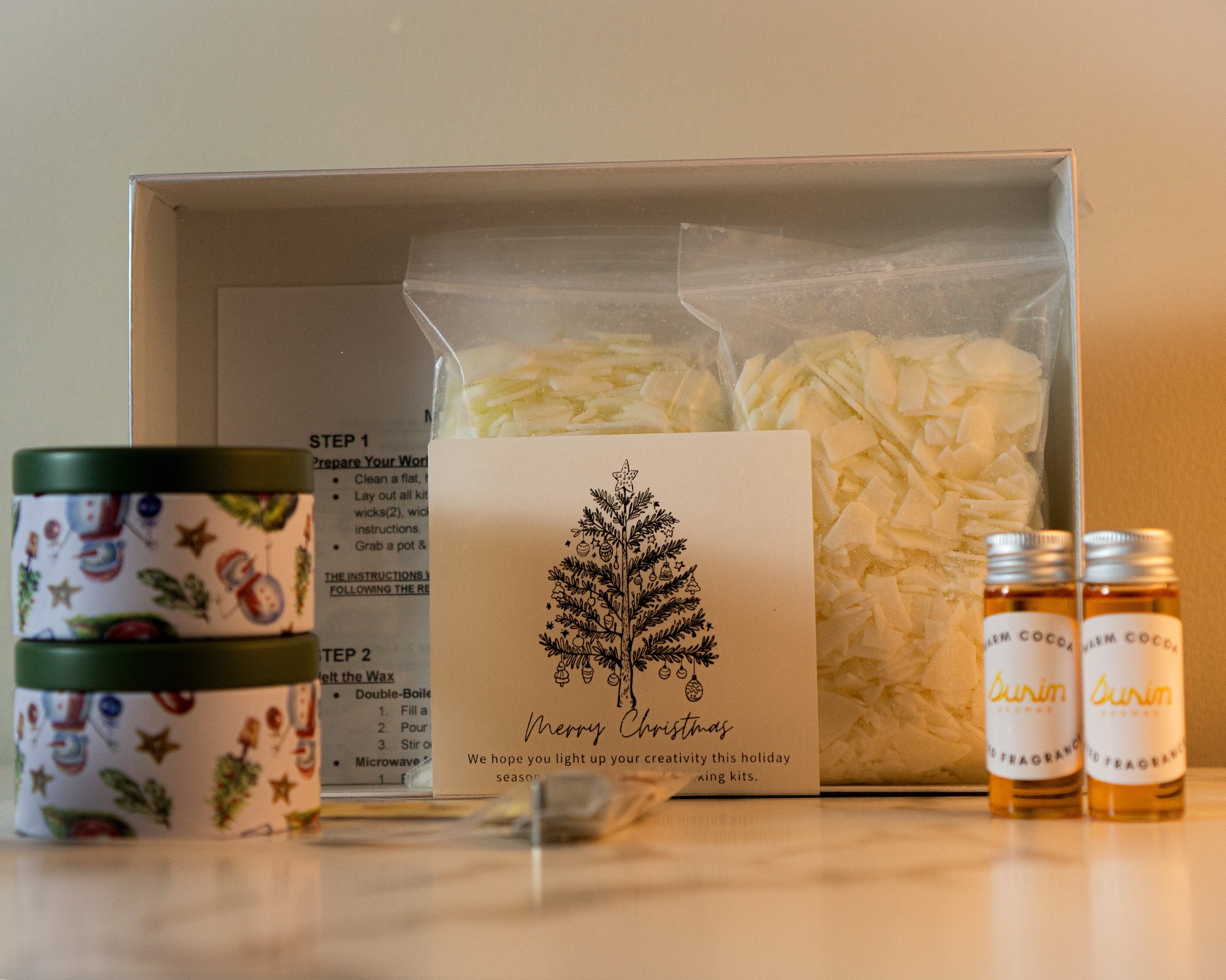 Gift set with candles, a card, and bottles on a white surface.