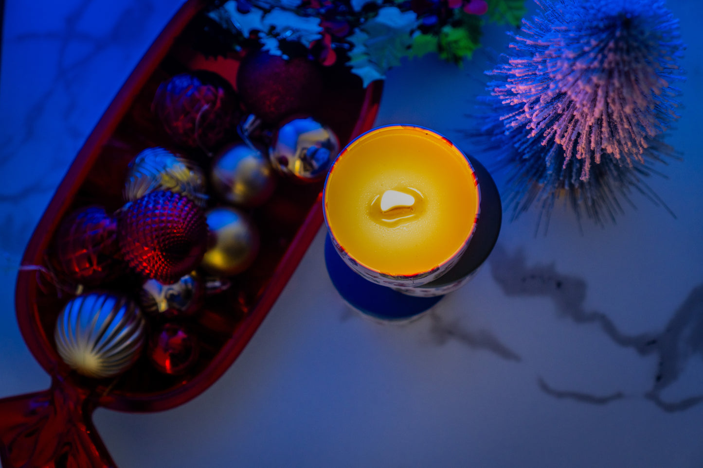 Candle with colorful ornaments on a textured surface