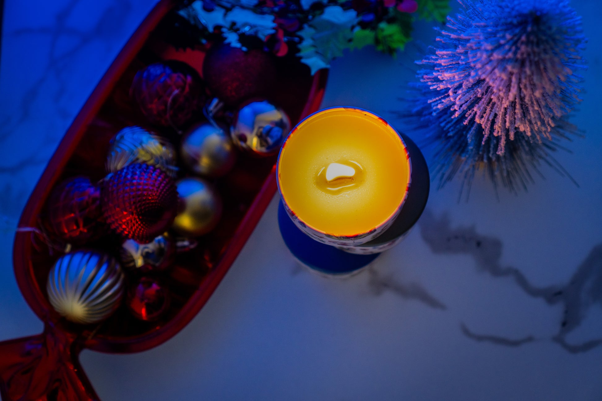 Candle with colorful ornaments on a textured surface